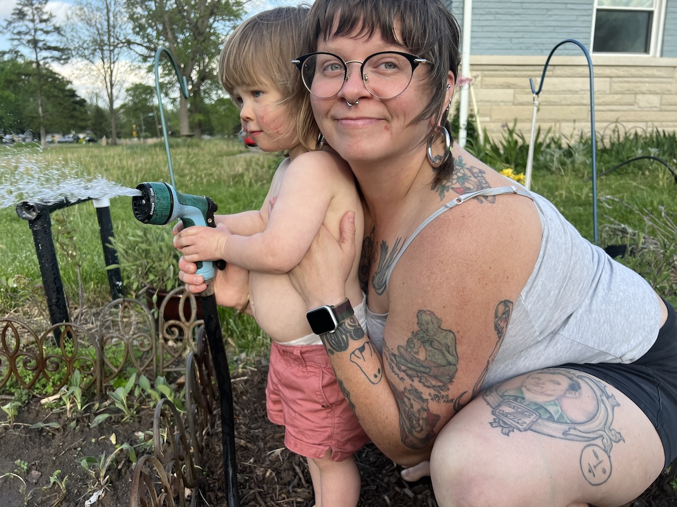 Robyn Lukens holding Dottie Lukens who is holding a hose spraying water