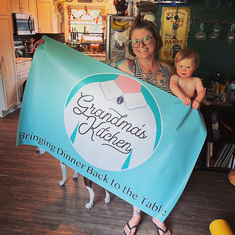Robyn and Dottie Lukens holding up a banner for Grandma's Kitchen